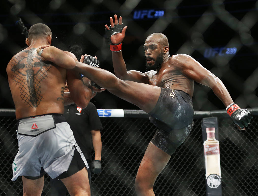 Jon Jones, right, lands a high kick against Thiago Santos in the first round during their light ...