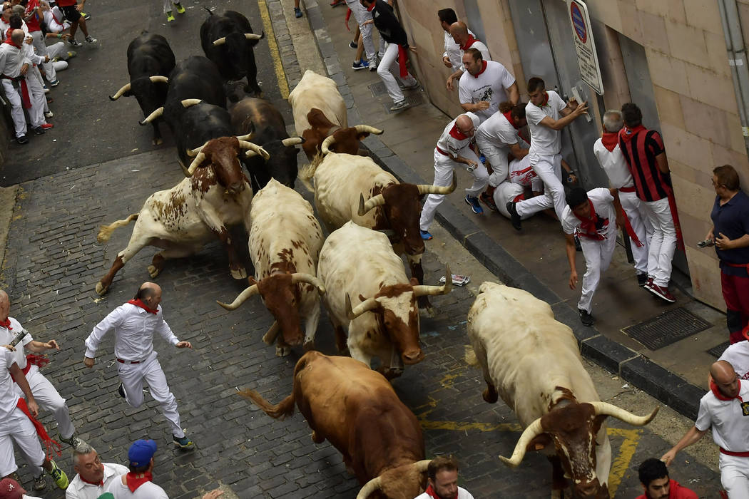 Revellers run next to fighting bulls during the running of the bulls at the San Fermin Festival ...