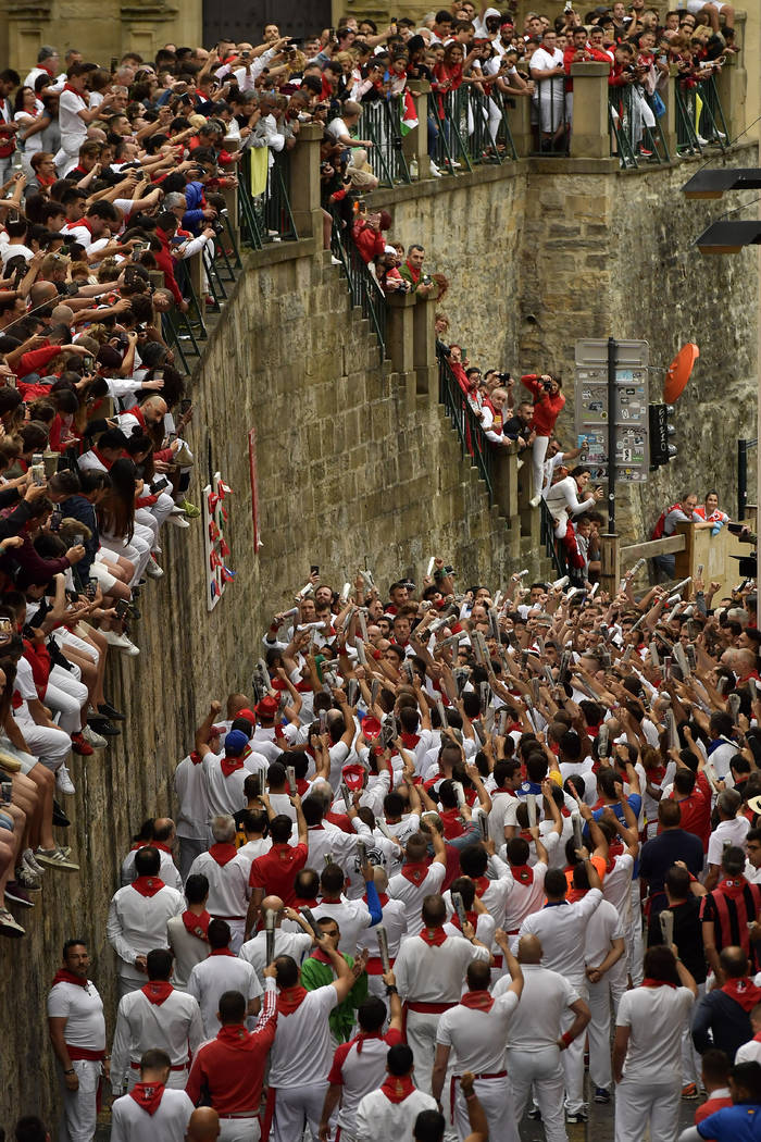 Revellers hold a rolled newspaper as they sing a song to San Fermin, bottom left, on Santo Domi ...