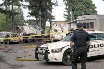 Port Angeles police Officer T.J. Mueller looks over the scene of a fire that destroyed two mobi ...