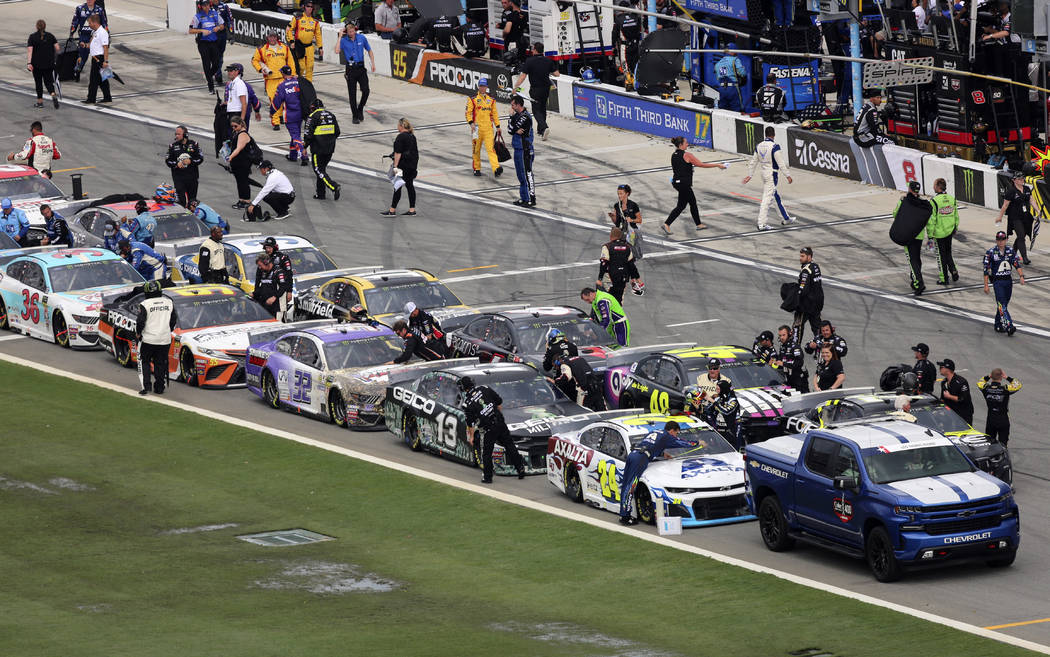 Pit crews begin to cover their cars on pit road as inclement weather moves in causing a delay i ...