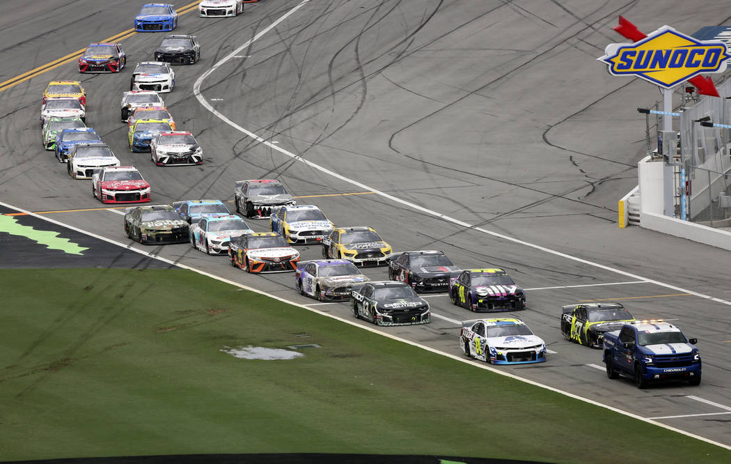 Cars file in behind the pace truck on pit road after the NASCAR Cup Series auto race was delaye ...