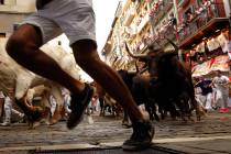 Revellers run next to fighting bulls from Cebada Gago ranch, during the running of the bulls at ...