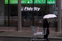 In a June 18, 2019, photo a man pulls a grocery cart as he walks in the rain past the stock tic ...