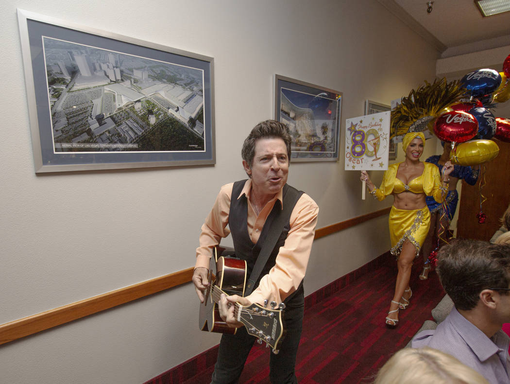 Elvis Impersonator Gregg Peterson plays guitar as showgirl Jennifer Gagliano, background,& ...