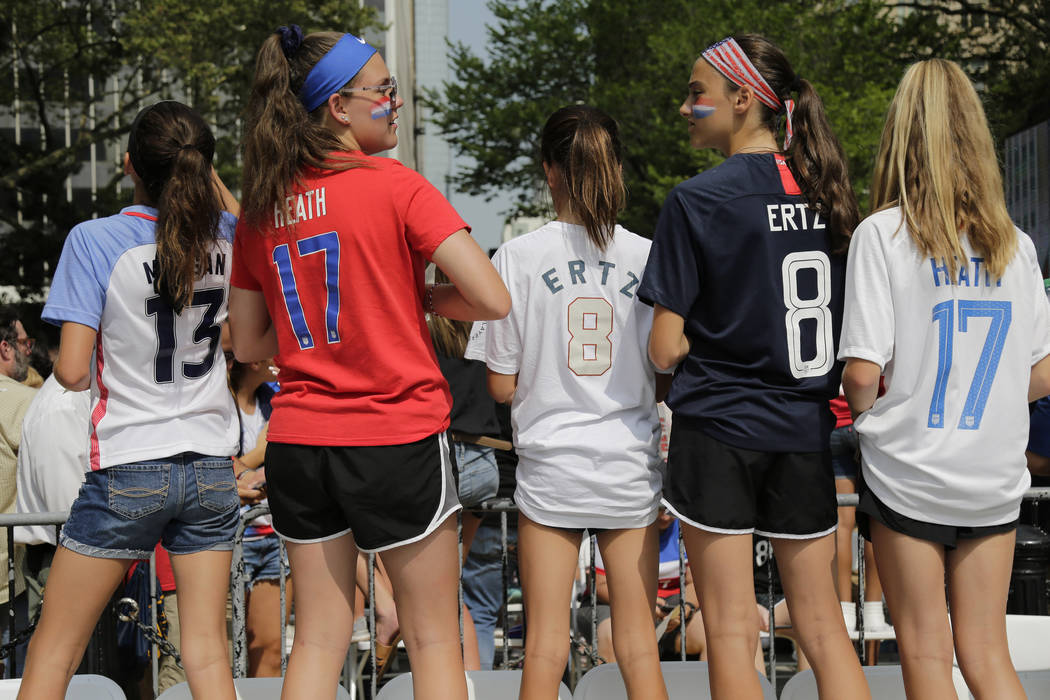 Girls in soccer jerseys wait for the arrival of the U.S. women's soccer team at City Hall, afte ...