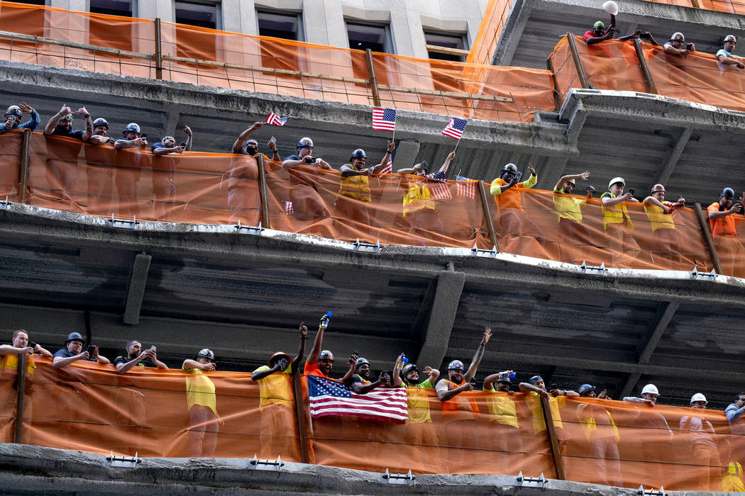 Construction workers watch as members of the U.S. women's soccer team is celebrated with a tick ...