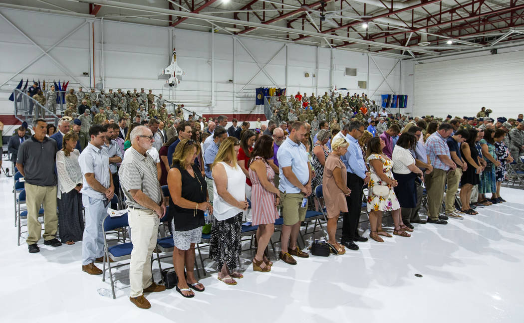 Family, friends and invited guests stand for a prayer during the Assumption of Command Ceremony ...