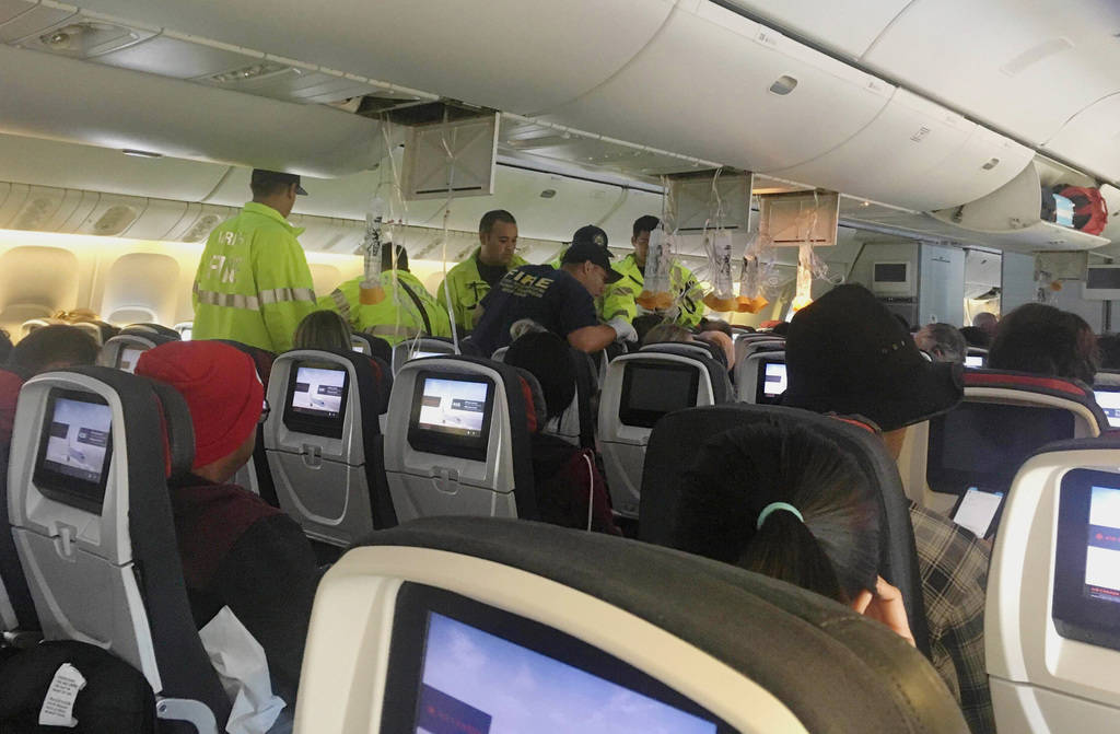 Emergency workers treat a passenger on an Air Canada flight to Australia that was diverted and ...