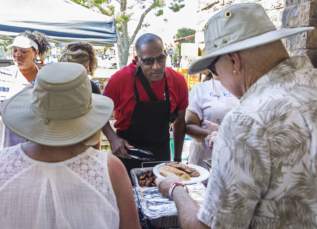 Clark County Commissioner Lawrence Weekly, middle, serves food to guests during the 5th Annual ...