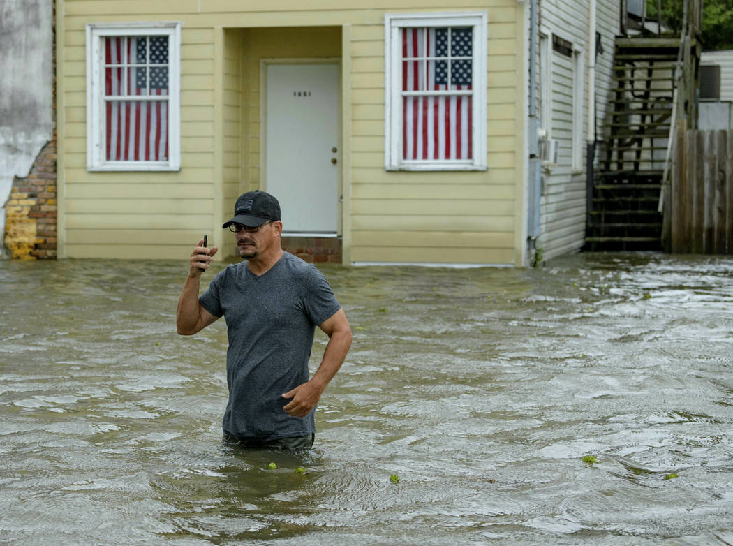 Barry Williams talks to a friend on his smartphone as he wades through storm surge from Lake Po ...