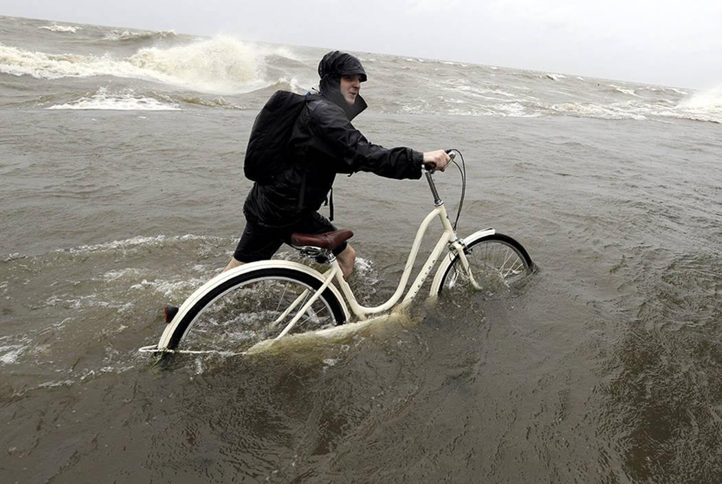 Tyler Holland guides his bike through the water as winds from Tropical Storm Barry push water f ...