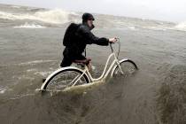 Tyler Holland guides his bike through the water as winds from Tropical Storm Barry push water f ...