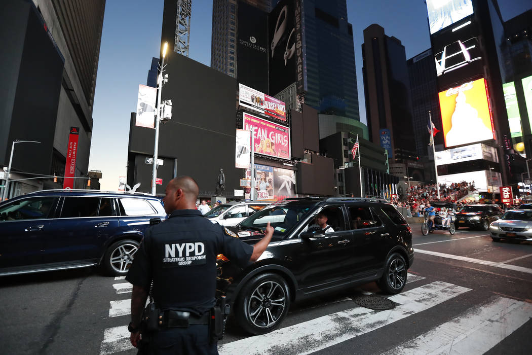 A police officer directs traffic in Times Square during a widespread power outage, Saturday, Ju ...