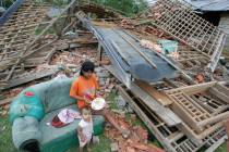 A woman feeds her daughter outside her house damaged by a strong earthquake in Lais, Bengkulu, ...