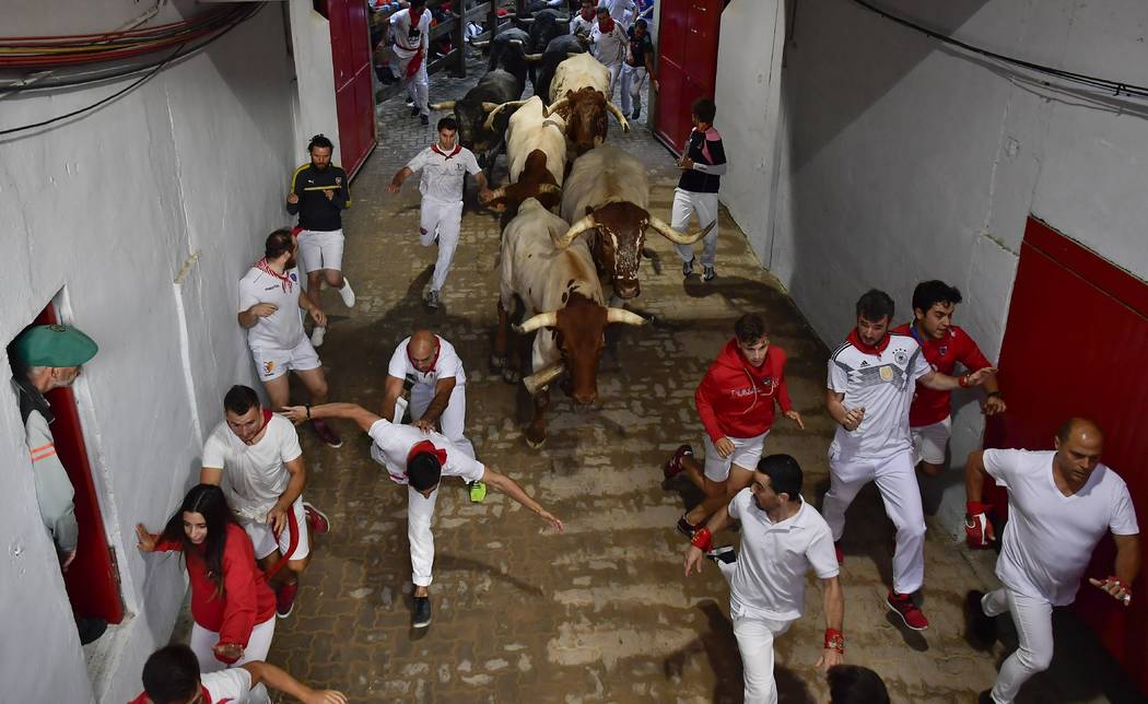 Revellers run next to fighting bulls during the running of the bulls at the San Fermin Festival ...