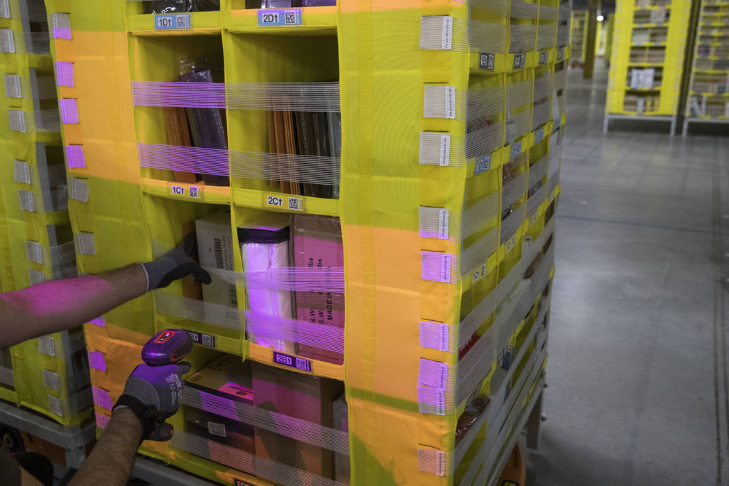A Dec. 5, 2018, file photo shows Amazon Stower Leo Esparragoza using colored light to help sort ...