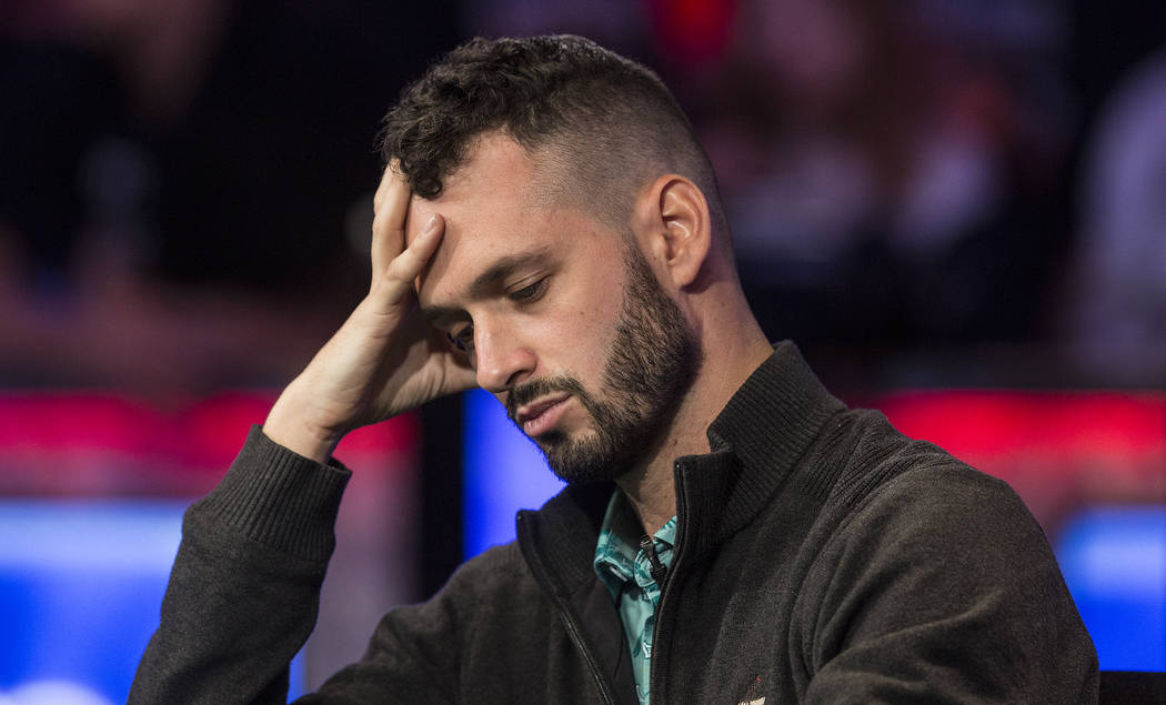 Alex Livingston, from Canada, looks at his cards during the World Series of Poker Main Event on ...