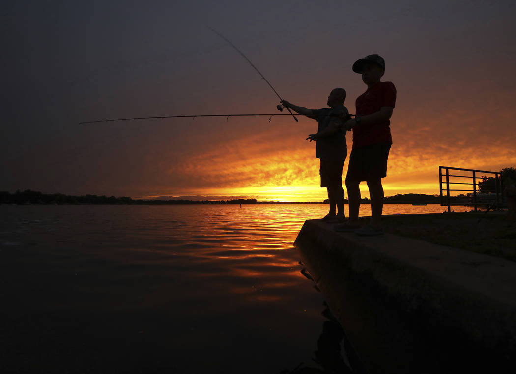 Jon Baucom and his son Connor fish the shores of Lac LaBelle in Oconomowoc, Wis., as the sun se ...