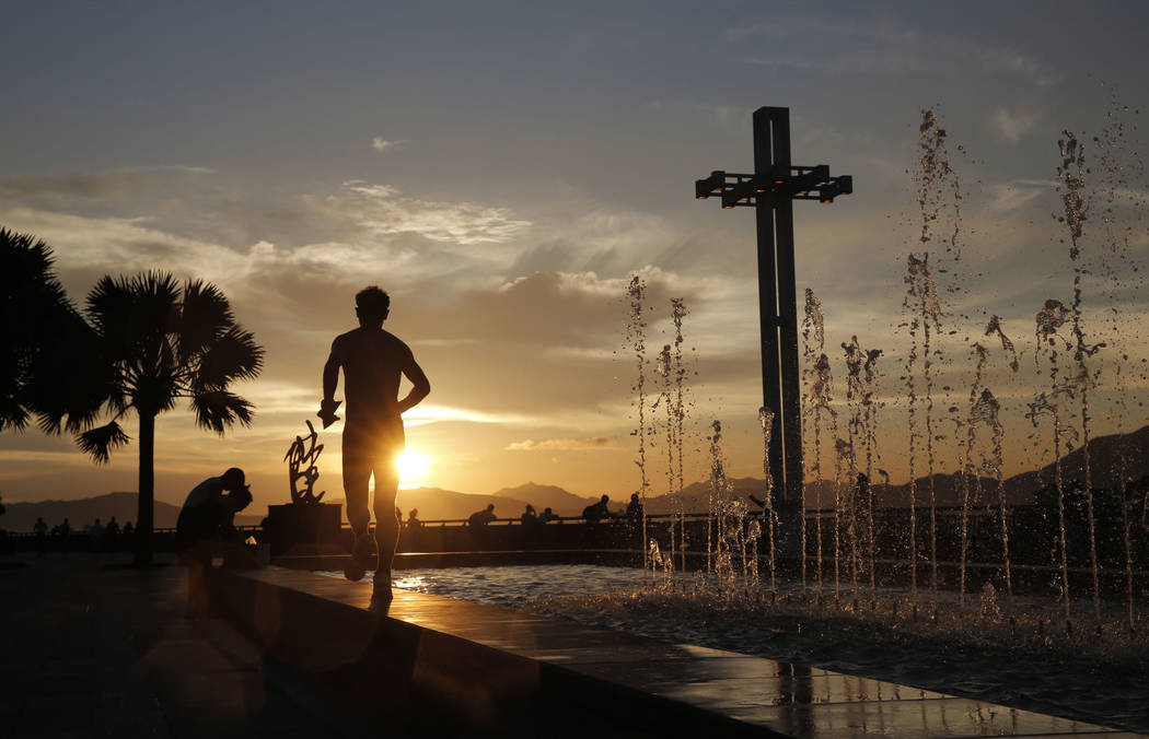 A man runs by a fountain during sunset at the waterfront of Victoria Harbor in Hong Kong, Wedne ...
