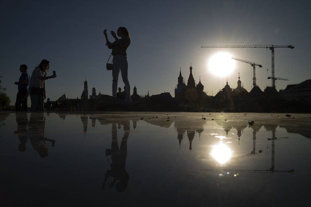 A woman poses for a photo at Zaryadye Park with the Kremlin in the background during a sunset i ...