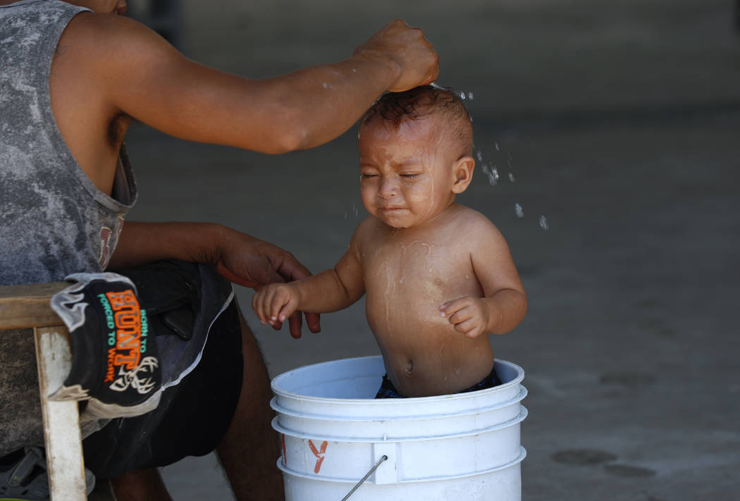 A migrant baby is given a bath at the AMAR migrant shelter in Nuevo Laredo, Mexico, Tuesday, Ju ...