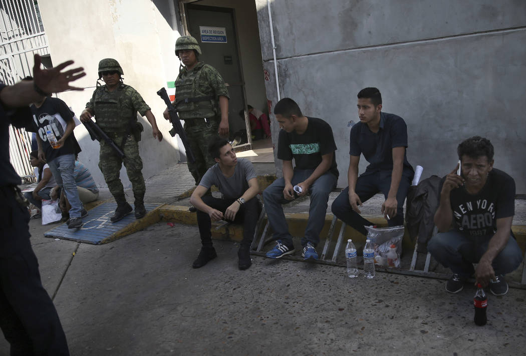 Migrants wait under guard at an immigration center on the International Bridge 1, as an immigra ...