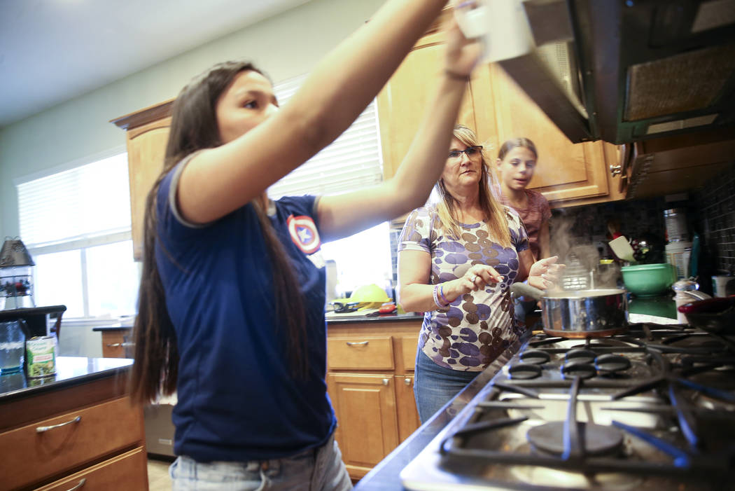 Anita Stephens, center, makes dinner with adopted daughters Serra Stephens, 14, left, and Abi S ...