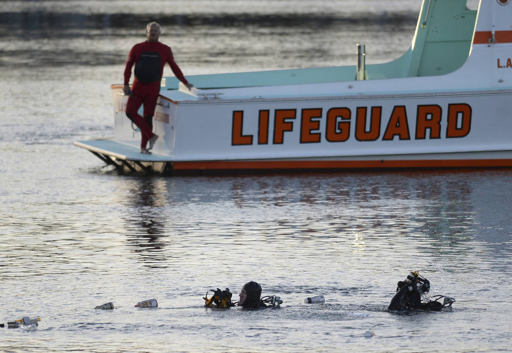 FILE - In this April 9, 2015 file photo, divers emerge from the water as debris believed to be ...