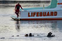 FILE - In this April 9, 2015 file photo, divers emerge from the water as debris believed to be ...