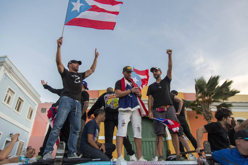 Singer Ricky Martin, left, waves the Puerto Rican flag during march against governor Ricardo Ro ...