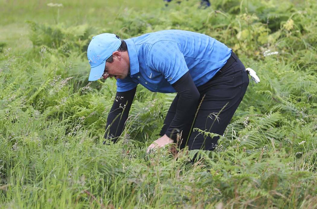 Northern Ireland's Rory McIlroy looks for his ball in the long rough on the 1st hole during the ...