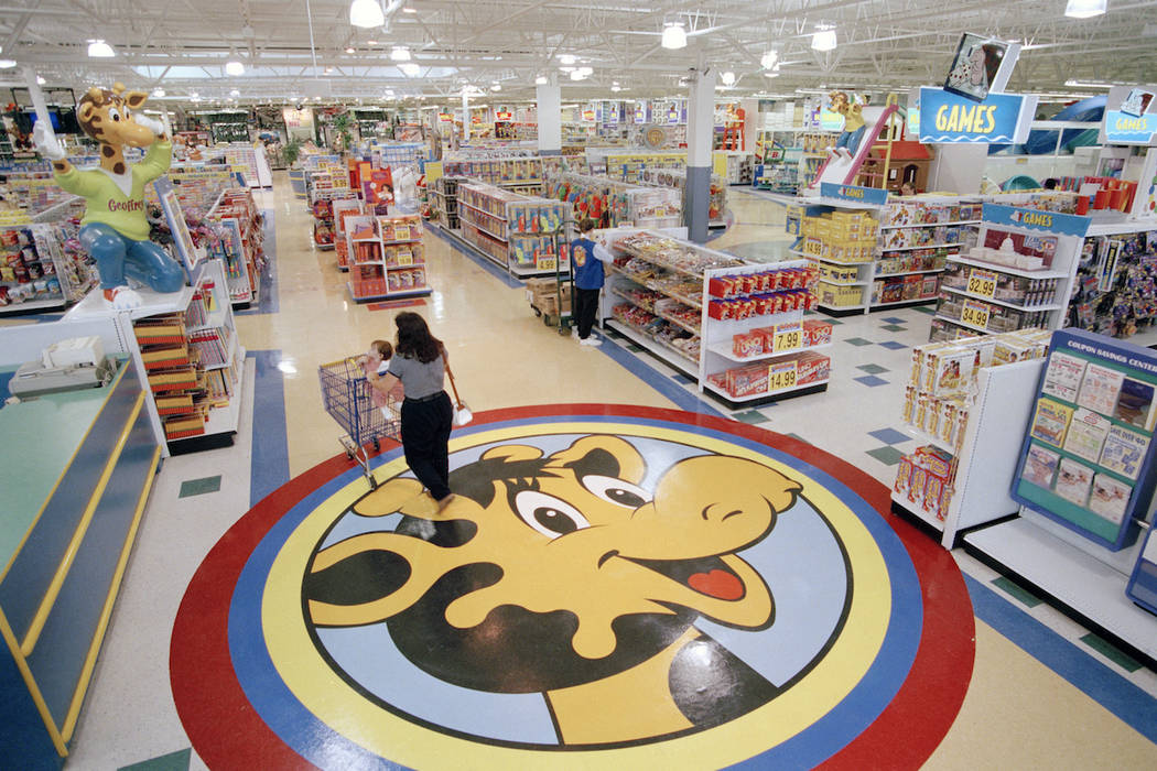 In this July 30, 1996, file photo, a woman pushes a shopping cart over a graphic of Toys R Us m ...