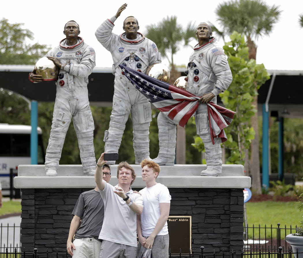 Guests take a selfie photo in front of a new statue of the the Apollo 11 astronauts, from left, ...