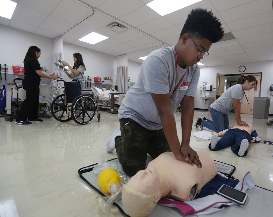 James Treadwell, 15, left, and Lea Jensen, 17, right, practice breathing on a medical doll at C ...