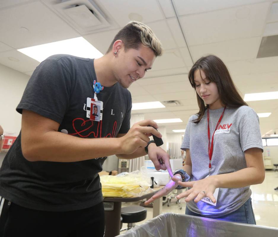 Nigel Cutting, 21, and summer camp student Mallory Gonzales, 17, right, checks the cleanliness ...