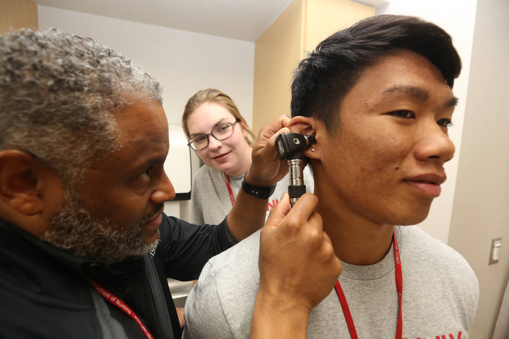 Dr. Aaron Bellow Jr., 45, checks the ears of student John Patriarca, 18, right, as Anabelle C ...