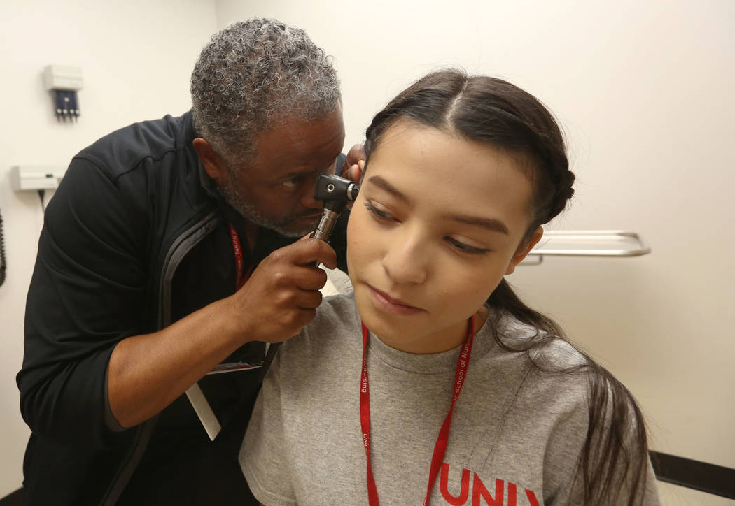 Dr. Aaron Bellow Jr., 45, practices on summer camp student Victoria Tarango, 17, at Clinical S ...