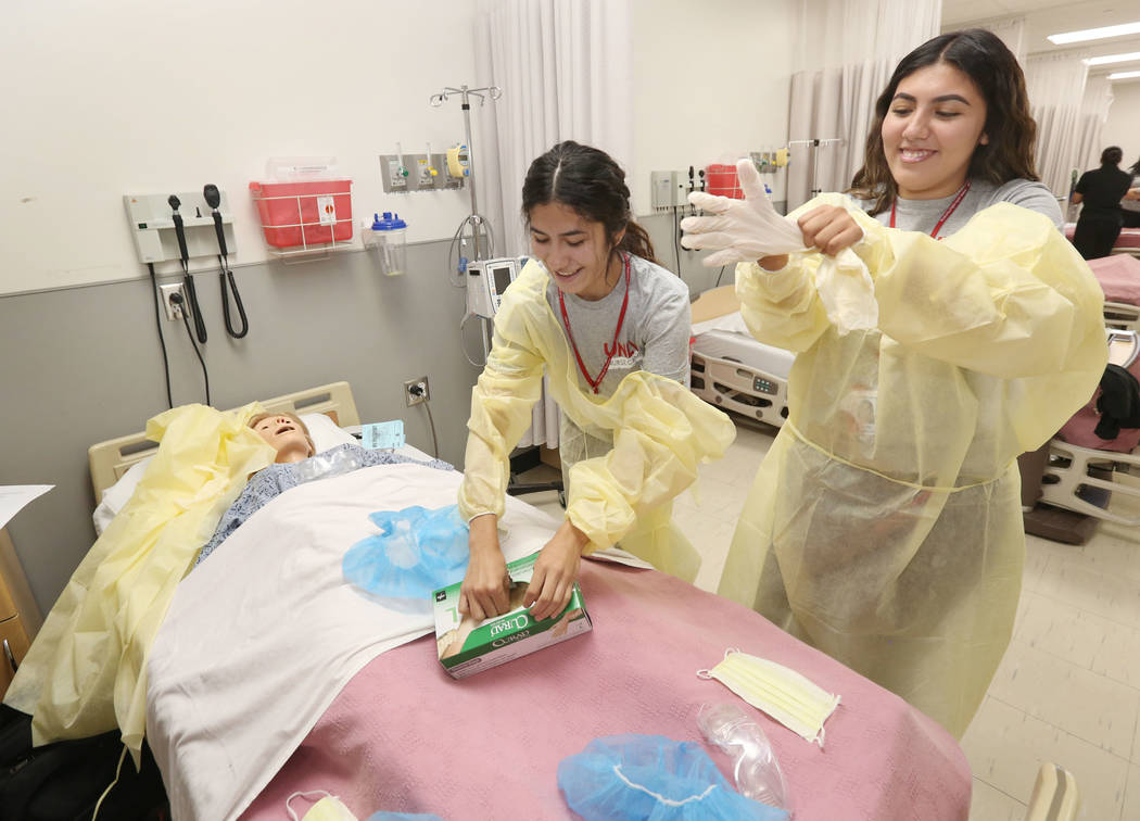 Brittany Renteria, 17, left, and Yareli Marquez, 17, right, practice putting on scrubs like med ...