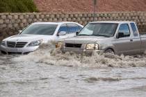 A truck makes its way past a vehicle stalled in floodwaters on West Twain Avenue near Dean Mart ...