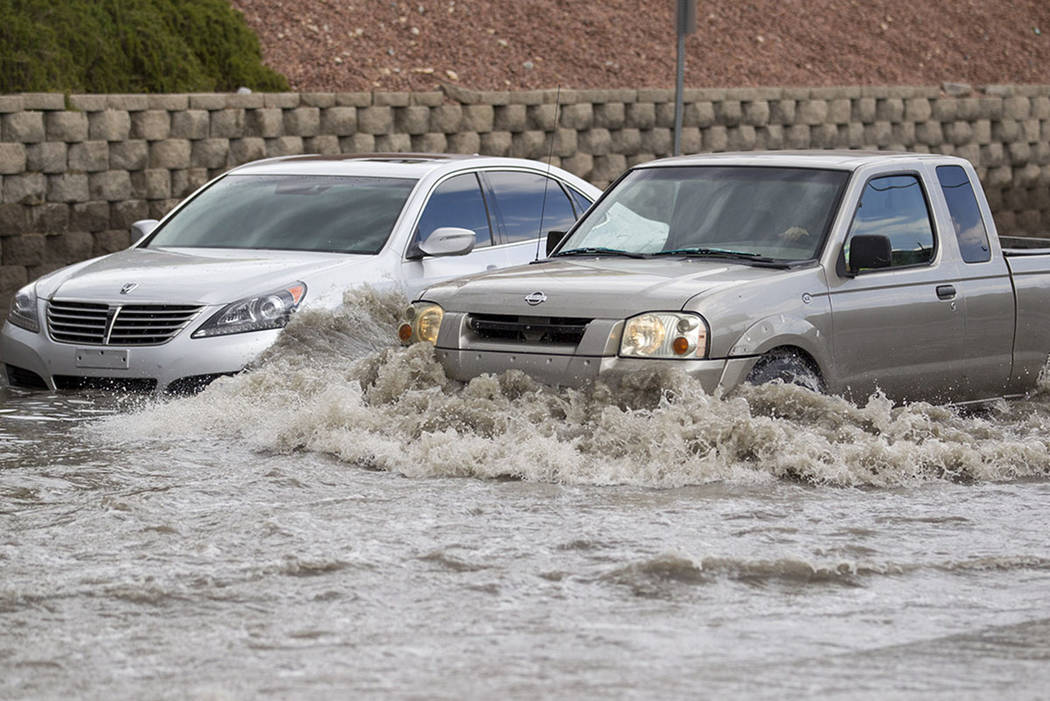 A truck makes its way past a vehicle stalled in floodwaters on West Twain Avenue near Dean Mart ...