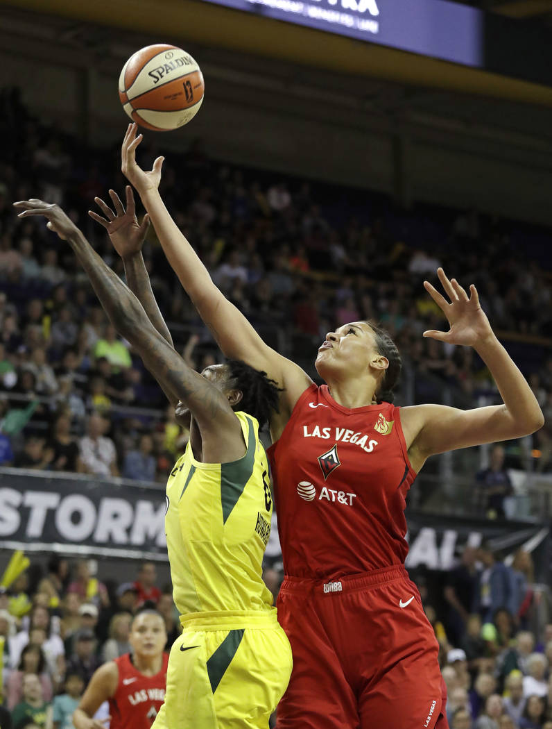Las Vegas Aces' Liz Cambage, right, reaches for a loose ball over Seattle Storm's Natasha Howar ...