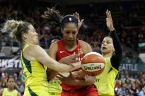 Las Vegas Aces' A'ja Wilson, center, fights for a loose ball with Seattle Storm's Sami Whitcomb ...