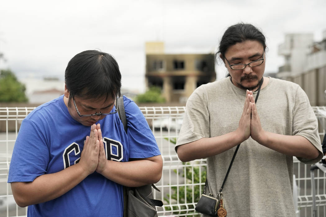 Two men pay respects at a makeshift memorial site to honor the victims of Thursday's fire at th ...