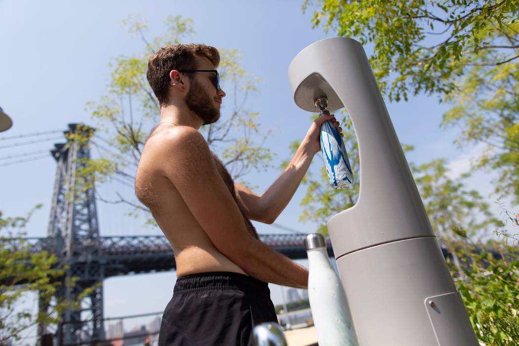 A man refills with water at a local park as temperatures reach the mid-to-upper 90's in William ...
