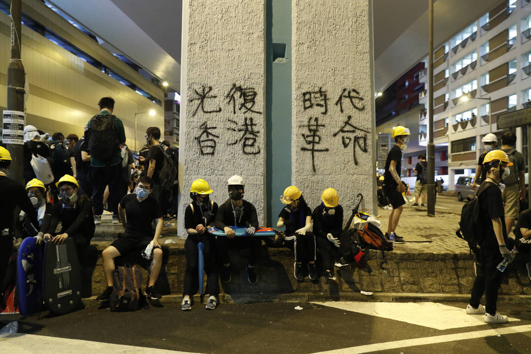 Protesters rest near graffiti which reads "Recovery of Hong Kong, An Era Revolution" ...