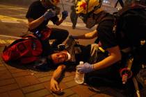Medical workers help a protester in pain from tear gas fired by policemen on a street in Hong K ...