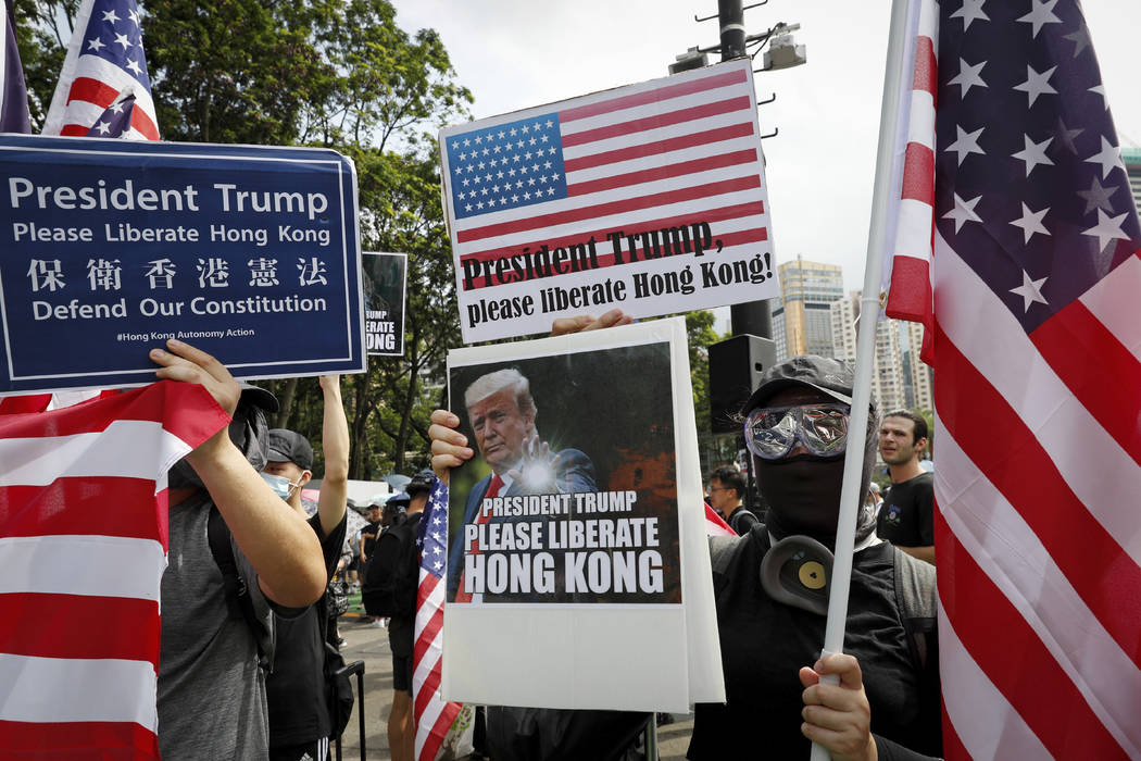 Protesters hold a placard featuring U.S. President Donald Trump and U.S. flags as they take par ...