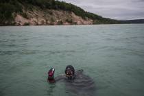 In a Thursday, July 11, 2019 photo, diver Chris Roxburgh of Traverse City picks up some golf ba ...