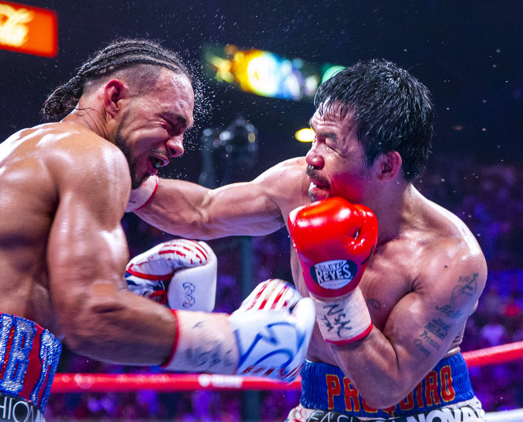 Keith Thurman, left, is punched in the face by Manny Pacquiao during Round 12 of their WBA supe ...